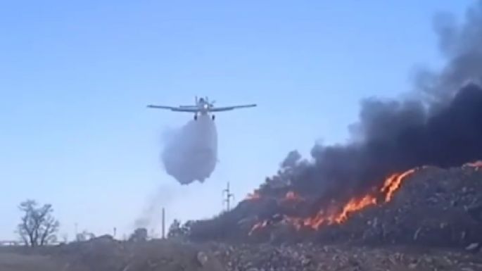 Bomberos y un avión trabajan para sofocar un incendio en el basural